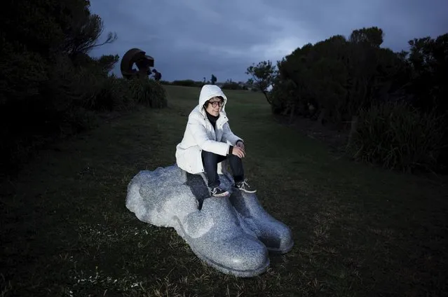 A visitor to Sydney's 19th annual Sculptures by the Sea exhibition sits on a granite sculpture entitled 'The first experience of a poet #3', October 23, 2015. (Photo by Jason Reed/Reuters)