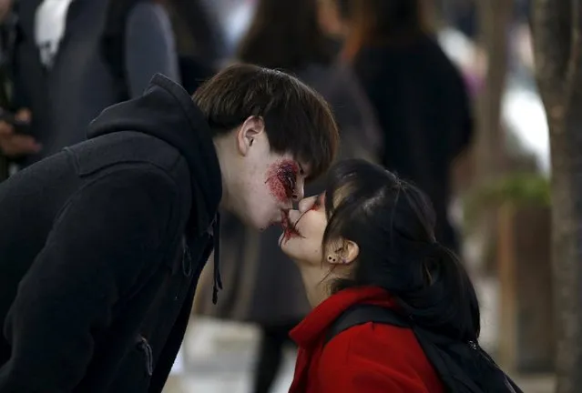 A man wearing Halloween face paint kisses his girlfriend during Halloween celebrations in the downtown of Seoul, South Korea, October 31, 2015. (Photo by Kim Hong-Ji/Reuters)