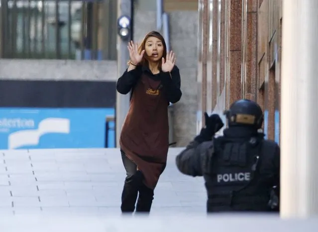 A hostage runs towards a police officer outside Lindt cafe, where other hostages are being held, in Martin Place in central Sydney December 15, 2014. Two more hostages have run out of the cafe at the center of a siege in Sydney, Australia's largest city, according to a Reuters witness at the site. (Photo by Jason Reed/Reuters)