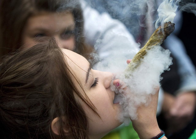 A woman smokes a large marijuana joint at the Vancouver Art Gallery during the annual 4/20 day, which promotes the use of marijuana, in Vancouver, British Columbia April 20, 2013. (Photo by Ben Nelms/Reuters)