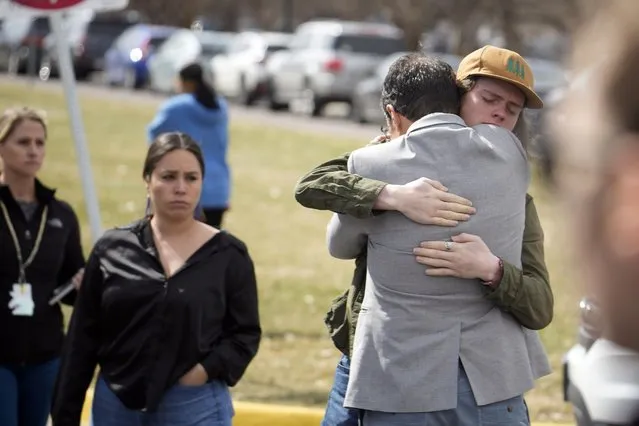 A student, right, hugs a parent as they are reunited following a shooting at East High School, Wednesday, March 22, 2023, in Denver. (Photo by David Zalubowski/AP Photo)