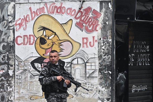 A Military Police officer patrols a street in the Cidade de Deus (City of God) favela, west zone of Rio de Janeiro, Brazil, on July 15, 2024. The Rio de Janeiro state government launched on Monday a vast police operation to “regain order” in ten favelas in the western part of the city, where drug traffickers and parapolice militias are fighting for territory. (Photo by Mauro Pimentel/AFP Photo)