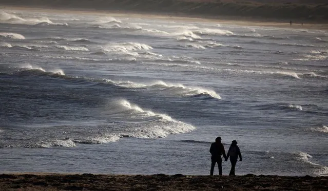 People walk along the beach near Redcar, Britain on January 30, 2023. (Photo by Phil Noble/Reuters)