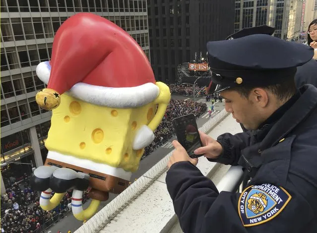 A New York Police Department officer takes a photo with his cellphone of a holiday-season themed float above 6th Ave during the 89th Macy's Thanksgiving Day Parade in the Manhattan borough of New York November 26, 2015. (Photo by Carlo Allegri/Reuters)