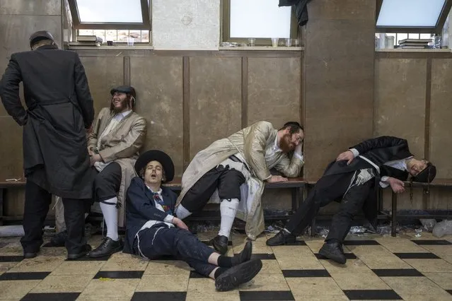 Ultra-orthodox Jewish men rest after getting drunk during celebrations of the Jewish holiday of Purim in Mea Shearim ultra-Orthodox neighborhood in Jerusalem, Wednesday, March 8, 2023. (Photo by Ohad Zwigenberg/AP Photo)