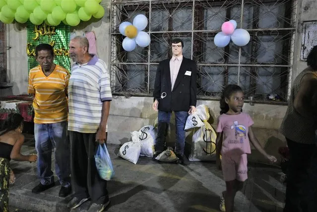 An effigy, labeled “corrupt one” surrounded with props representing bags of money is displayed on a sidewalk before it is ignited during the traditional “Burning of Judas” celebrations in the San Augustin neighborhood of Caracas, Venezuela, Sunday, April 9, 2023. Originally, the burning figures were effigies of Judas Iscariot, the apostle who is said to have betrayed Jesus Christ. Nowadays, though, artisans shape their “Judas” like as horned devils or other characters considered evil by society. (Photo by Ariana Cubillos/AP Photo)