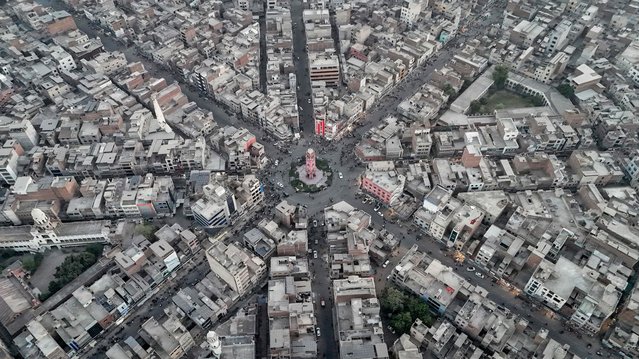 An aerial view shows commuters driving through a clock tower (C), formerly known as the Lyallpur Clock Tower, in Faisalabad in Pakistan's Punjab province on November 7, 2025. (Photo by Aamir Qureshi/AFP Photo)