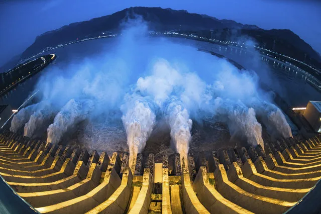 In this image made with fisheye lens and provided by Xinhua News Agency, floodwaters are discharged at the Three Gorges Dam in central China's Hubei province on Sunday, July 19, 2020. Authorities in the neighboring province of Anhui blasted a dam Sunday to release surging waters behind it amid widespread flooding across the country that has claimed scores of lives. (Photo by Xiao Yijiu/Xinhua via AP Photo)