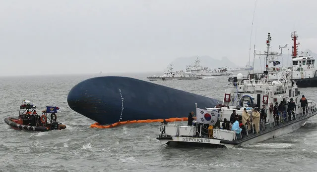 In this April 17, 2014 file photo, South Korean Coast Guard personnel search for missing passengers aboard the sunken South Korean ferry Sewol in the water off Jindo, South Korea. Salvage workers are slowly pulling up the huge, corroded South Korean ferry above the sea surface Thursday, March 23, 2017, about three years after it sank on its routine voyage to a resort island, killing more than 300 people, mostly high school students. (Photo by Ahn Young-joon/AP Photo)