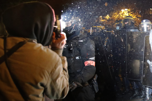 In this November 21, 2020 file photo a demonstrator takes a picture of policemen during a protest against bill on police images, in Paris. As videos helped reveal many cases of police brutality, French civil rights activists voiced fears that a new security law would threaten efforts by people from minorities and poor neighborhoods to document incidents involving law enforcement officers. French President Emmanuel Macron's government is pushing a new security bill that would notably make it illegal to publish images of officers with intent to cause them harm. (Photo by Christophe Ena/AP Photo/File)