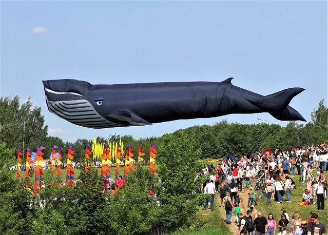 People walk next to a whale-shaped kite in the air, during the “Colorful sky” kite festival in Moscow, Russia on May 27, 2023. (Photo by Evgenia Novozhenina/Reuters)