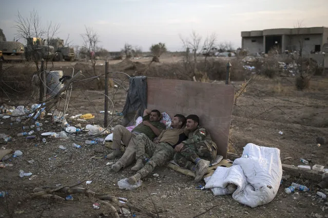 Kurdish Peshmerga fighters rest on the side of the road after taking the city from Islamic State militants in Bashiqa, east of Mosul, Iraq, Friday, November 11, 2016. (Photo by Felipe Dana/AP Photo)