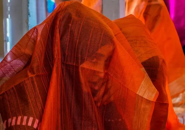 A Kashmiri Muslim bride looks through her veil during a mass wedding event in Srinagar, Indian controlled Kashmir, Thursday, June 15, 2023. Mass weddings in India are organized by social organizations primarily to help the economically backward families who cannot afford the high ceremony costs as well as the customary dowry and expensive gifts that are still prevalent in many communities. (Photo by Mukhtar Khan/AP Photo)