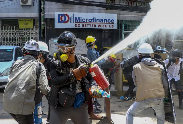 Anti-coup protesters discharge fire extinguishers to counter the impact of the tear gas fired by police during a demonstration in Yangon, Myanmar Thursday, March 4, 2021. (Photo by AP Photo/Stringer)