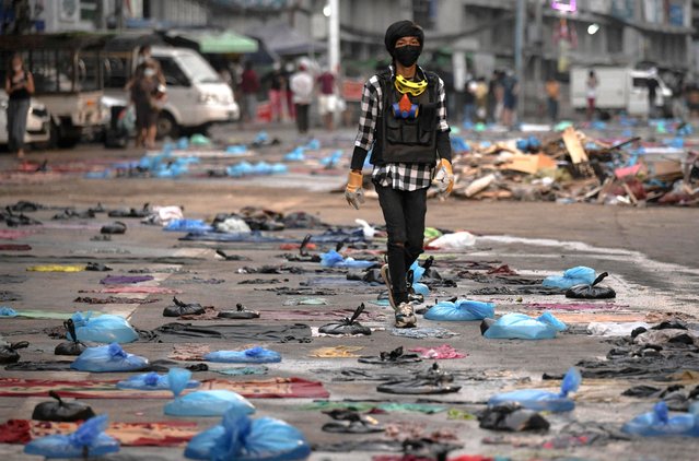 A protester walks in a street full of water bags to be used against tear gas, during an anti-coup protest at Hledan junction in Yangon, Myanmar, March 14, 2021. (Photo by Reuters/Stringer)