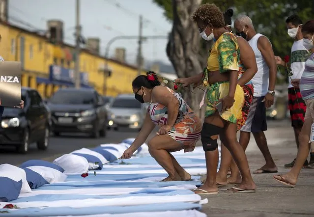 Residents place roses on mattresses symbolizing COVID-19 victims, during a protest against the Government's handling of the COVID-19 pandemic, organized by the Rio de Paz NGO, in front of the Ronaldo Gazolla hospital in Rio de Janeiro, Brazil, Wednesday, March 24, 2021. (Photo by Silvia Izquierdo/AP Photo)