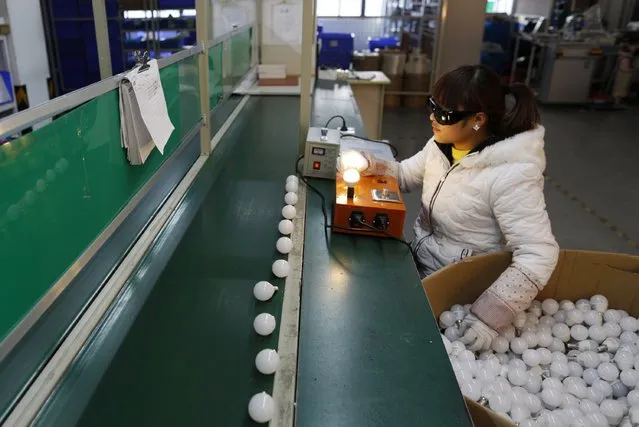 An employee tests newly-made light bulbs along a production line of a factory in Jiaxing, Zhejiang province February 6, 2015. (Photo by William Hong/Reuters)