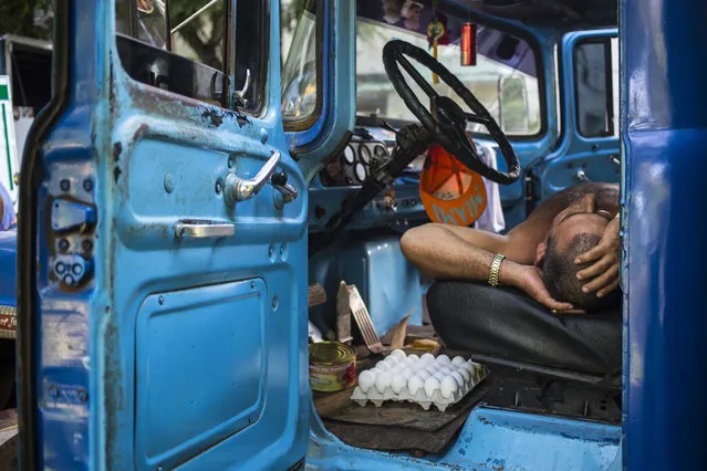 A truck driver takes a nap in the cabin of his truck at an outdoor food market in Havana, Cuba, Saturday, July 21, 2018. Cuban lawmakers on Saturday approved the Cabinet named by new President Miguel Diaz-Canel, keeping most of the ministers from Raul Castro's government in place. (Photo by Desmond Boylan/AP Photo)
