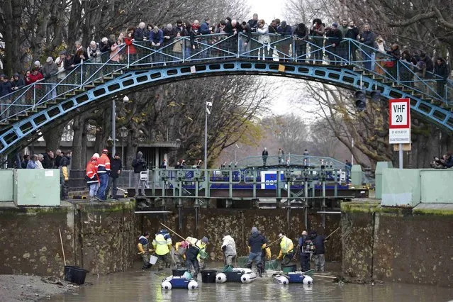 Journalists and passers-by watch as workers catch fish near a lock during the draining of the Canal Saint-Martin in Paris, France, January 6, 2016. Authorities have started a three-month cleanup operation of the canal St-Martin, in north-eastern Paris, in an attempt to refurbish its locks and remove rubbish. (Photo by Charles Platiau/Reuters)