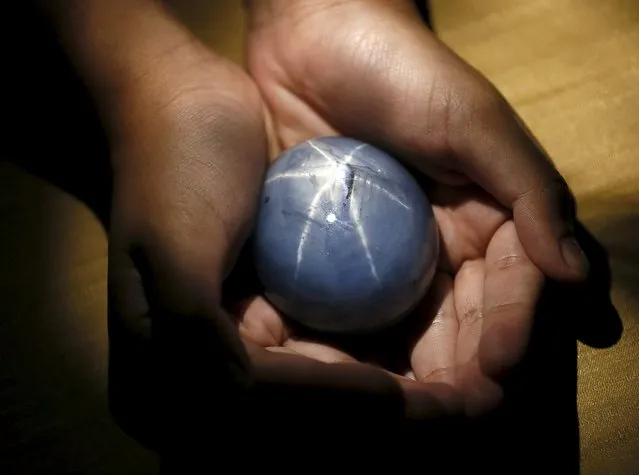 The owner of the world's largest blue sapphire holds it for photographs during an interview with Reuters in Colombo January 6, 2016. The owner of the world's largest blue sapphire, which he says is worth more than $100 million, said on Thursday he is deciding whether to auction the Sri Lankan gem or display it as an international attraction. (Photo by Dinuka Liyanawatte/Reuters)