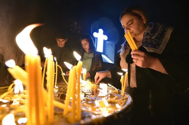 Armenian Christian worshippers light candles during an Easter religious service in Yerevan on April 4, 2021. Millions of Christians around the world celebrated a second Easter under coronavirus restrictions on Sunday with Pope Francis calling for vaccines to be shared among the poorest nations as Covid-19 surges. (Photo by Karen Minasyan/AFP Photo)