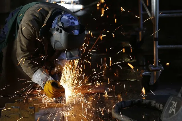 A ship builder works on a section of the Oasis Class 3 cruise ship under construction at the STX Les Chantiers de l'Atlantique shipyard site in Saint-Nazaire, western France, February 17, 2015. (Photo by Stephane Mahe/Reuters)