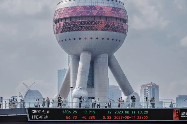 People walk on a pedestrian bridge with a screen showing stock exchange data, in Shanghai, China, 21 August 2023. Asian markets faced a setback on 21 August as China's reduction in lending rates proved to be smaller than anticipated. This extends Beijing's trend of providing stimulus measures that are more conservative than expected. The one-year loan prime rate (LPR) experienced a ten basis points reduction by the People's Bank of China, whereas the unchanged five-year rate, employed in calculating mortgage expenses, remained steady. (Photo by Alex Plavevski/EPA)