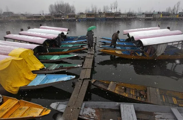 A man boards a boat as another holding an umbrella walks on a jetty on the Dal Lake during snowfall in Srinagar February 19, 2015. (Photo by Danish Ismail/Reuters)