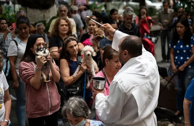 A Catholic priest sprinkles holy water on parishioners who attend a mass to bless their pets at the Church of San Jose in front of Bolivar Square in the Chacao neighborhood during World Animal Day in Caracas on October 4, 2023. (Photo by Yuri Cortez/AFP Photo)