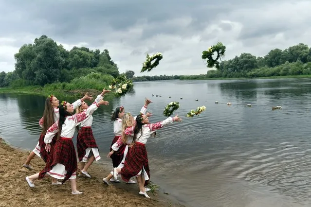 Belarusian women in national costumes throw wreaths into the water the Berezina River on Ivan Kupala Day, an ancient night long celebration marking the Summer Solstice, the shortest night of the year, in Parichi village, some 200 km (125 miles) south of Parichi, Belarus, Wednesday, July 6, 2022. (Photo by Viktor Drachev/AP Photo)