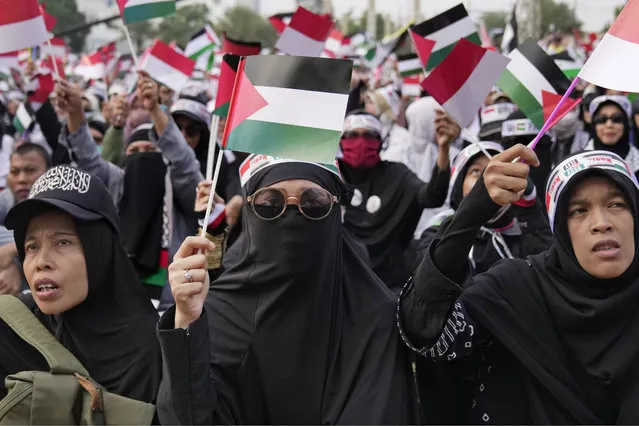 Muslim women wave Palestinian and Indonesian flags during a rally supporting the Palestinians in Jakarta, Indonesia, Sunday, October 15, 2023. (Photo by Dita Alangkara/AP Photo)