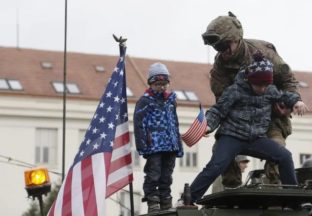 A US army soldier helps a kid on top of a stryker armored vehicle during a stop of his convoy in Prague, Czech Republic, Tuesday, March 31, 2015. (Photo by Petr David Josek/AP Photo)