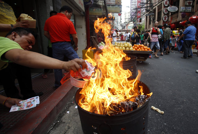 Filipino-Chinese residents burn paper money on the eve of the Chinese New Year celebration in Manila's Chinatown, Philippines February 7, 2016. (Photo by Erik De Castro/Reuters)
