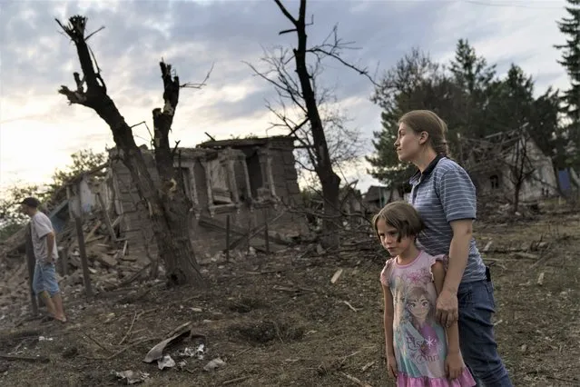 Residents look at damaged homes from a rocket attack early this morning, Tuesday, August 16, 2022, in Kramatorsk, eastern Ukraine, as Russian shelling continued to hit towns and villages in Donetsk province, regional officials said. (Photo by David Goldman/AP Photo)