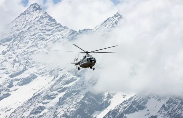 In this Monday, April 6, 2015 photo, a Russian MI 17 chopper, carrying cargo for Everest expeditions, flies in front of Mount Thamserku in Syangboche, Nepal. Climbers are returning to Mount Everest as the climbing industry recovers from last year's deadly disaster on the world's highest peak, a Nepalese mountaineering official said on April 1. The popular spring climbing season began last month and runs until the end of May. (Photo by Tashi Sherpa/AP Photo)