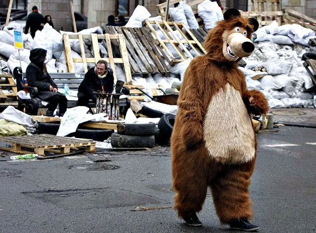 A man dressed as a bear, walks near a barricade during a gathering of pro-European integration protesters, while waiting for paid photographs with tourists, in central Kiev December 16, 2013. The opposition went ahead with preparations for another big rally for Tuesday against what they see as moves by President Viktor Yanukovich to sell out national interests to Russia after backing away from a landmark deal with the European Union that would have shifted their country westwards. (Photo by Gleb Garanich/Reuters)