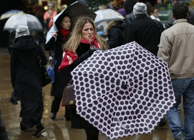 Shoppers walk in wet and windy weather on Oxford Street in central London December 23, 2013. (Photo by Olivia Harris/Reuters)