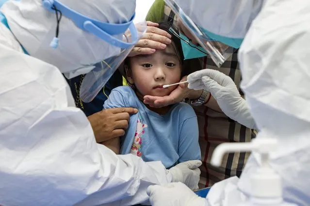 A child reacts to a throat swab during mass testing for COVID-19 in Wuhan in central China's Hubei province Tuesday, August 3, 2021. The coronavirus’s delta variant is challenging China’s costly strategy of isolating cities, prompting warnings that Chinese leaders who were confident they could keep the virus out of the country need a less disruptive approach. (Photo by Chinatopix via AP Photo)