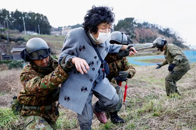 Residents in Fukamimachi, a village isolated after the earthquake, are helped by members of Japan Self-Defense Forces (JSDF) as they head to a rescue helicopter, in Wajima, Ishikawa Prefecture, Japan on January 6, 2024. (Photo by Kim Kyung-Hoon/Reuters)
