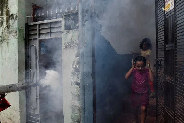 Children react surrounded by a vapor cloud during a fumigation operation held by Dhaka City Corporation in Dhaka, Bangladesh on October 12, 2023. (Photo by Fatima Tuj Johora/Reuters)