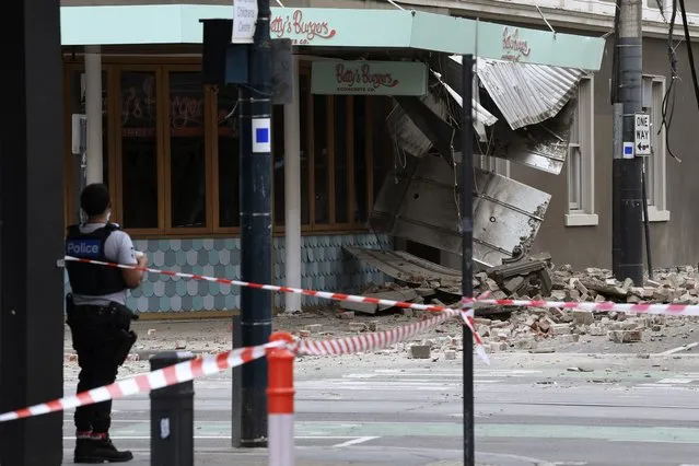 A police officer closes an intersection where debris is scattered in the road after an earthquake damaged a building in Melbourne, Wednesday, September 22, 2021. A magnitude 5.8 earthquake caused damage in the city of Melbourne in an unusually powerful temblor for Australia, Geoscience Australia said. (Photo by James Ross/AAP Image via AP Photo)