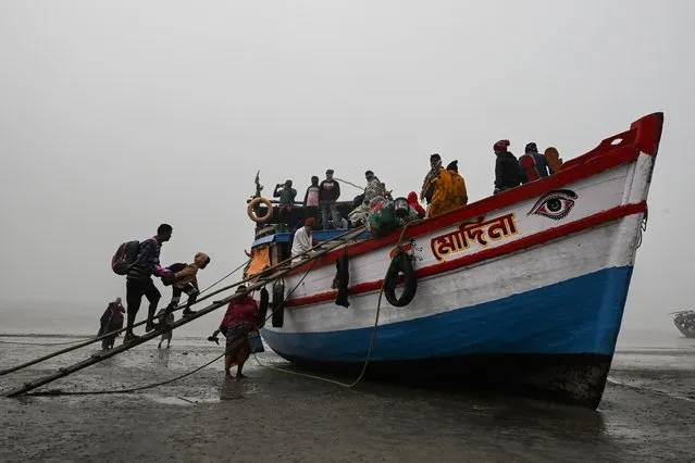Hindu pilgrims walk board a boat at the confluence of River Ganges and the Bay of Bengal after attending the Gangasagar mela in Sagar Island, some 150 kms South of Kolkata on January 16, 2024. (Photo by Dibyangshu Sarkar/AFP Photo)