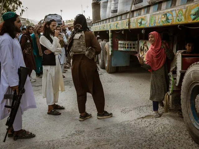 Taliban fighters scold a girl who hid behind the wheels of a truck in an attempt to cross into Pakistan to sell various products at the Torkham border post on August 21, 2021. (Photos by Sarah Caron/The Washington Post)