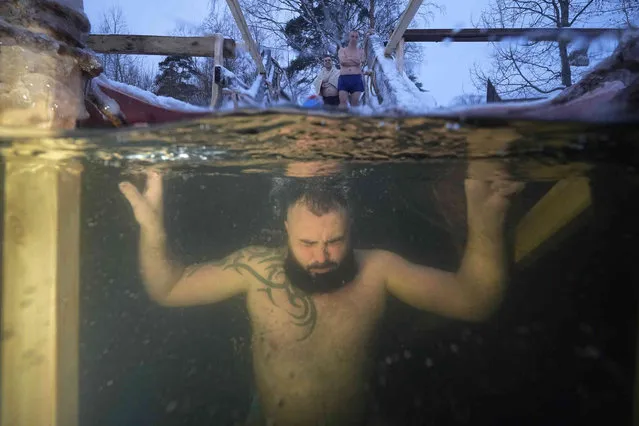 A Russian Orthodox believer dips in the icy water during a traditional Epiphany celebration, in St. Petersburg, Russia, Friday, January 19, 2024. Thousands of Russian Orthodox Church followers plunged into icy rivers and ponds across the country to mark Epiphany, cleansing themselves with water deemed holy for the day. The temperature in St.Petersburg is –4 Celsius (24 Fahrenheit). (Photo by Dmitri Lovetsky/AP Photo)