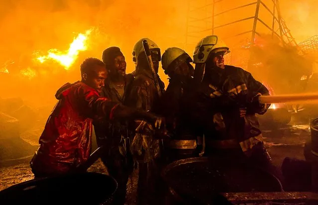 Firefighters and volunteers attempt to extinguish a fire that broke out at a commercial depot, used for oil barrels and flammable drums, near Muthurwa settlement, in Nairobi, Kenya, on January 30, 2024. (Photo by Thomas Mukoya/Reuters)