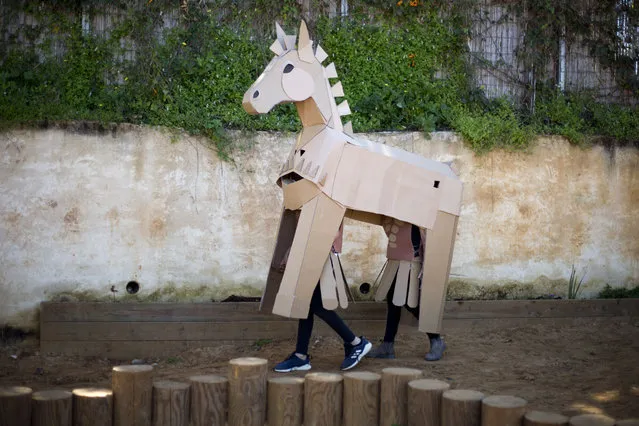 Merkaz Ofek School children wear recycled cardboard shaped costume of a trojan horse during the Purim parade festival in Eliyashiv, Hefer Valley, Israel, Tuesday, March 19, 2019. The Jewish holiday of Purim commemorates the Jews' salvation from genocide in ancient Persia, as recounted in the Book of Esther, which is read in synagogues. Other customs include: sending food parcels and giving charity, dressing up in masks and costumes, eating a festive meal, and public celebrations. (Photo by Ariel Schalit/AP Photo)