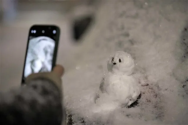 A person takes a photo of the snowman during snowfall in London, United Kingdom on December 11, 2022. Officials announced that the most effective snowfall since 2013 is expected across the country. (Photo by Rasid Necati Aslim/Anadolu Agency via Getty Images)