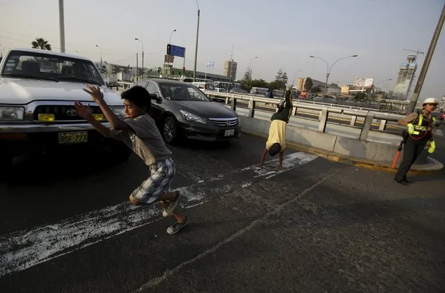 A boy somersaults at a traffic junction in Lima April 27, 2015. Children often perform on streets in Peru to make a living from tips given by drivers. (Photo by Mariana Bazo/Reuters)