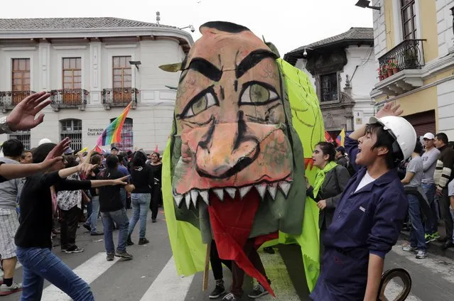 Marchers shout anti-government slogans as they dance with a Chinese dragon representing Ecuador's President Rafael Correa for his many collaborations with the Chinese government, during a march called by labor unions to mark May Day, in Quito, Ecuador, Friday, May 1, 2015. Rallies were staged around the world Friday to mark International Workers Day, also known as May Day. (Photo by Dolores Ochoa/AP Photo)