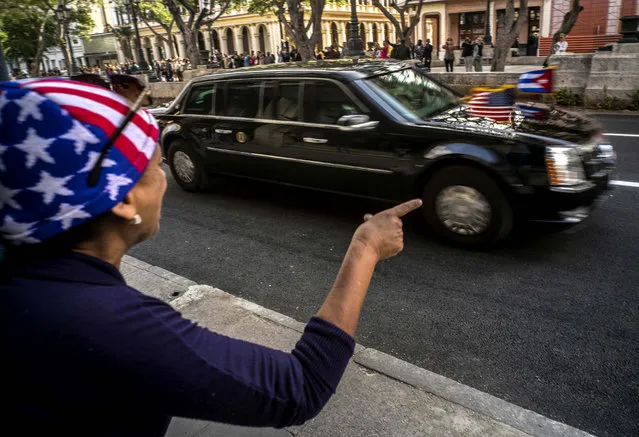 A woman points out the U.S. presidential limousine carrying President Barack Obama, as he arrives to the Grand Theater of Havana, Cuba,Tuesday, March 22, 2016. In his speech President Obama urged Cubans to look to the future with hope, casting his historic visit to the island nation as a moment to “bury the last remnants of the Cold War in the Americas”. (Photo by Ramon Espinosa/AP Photo)